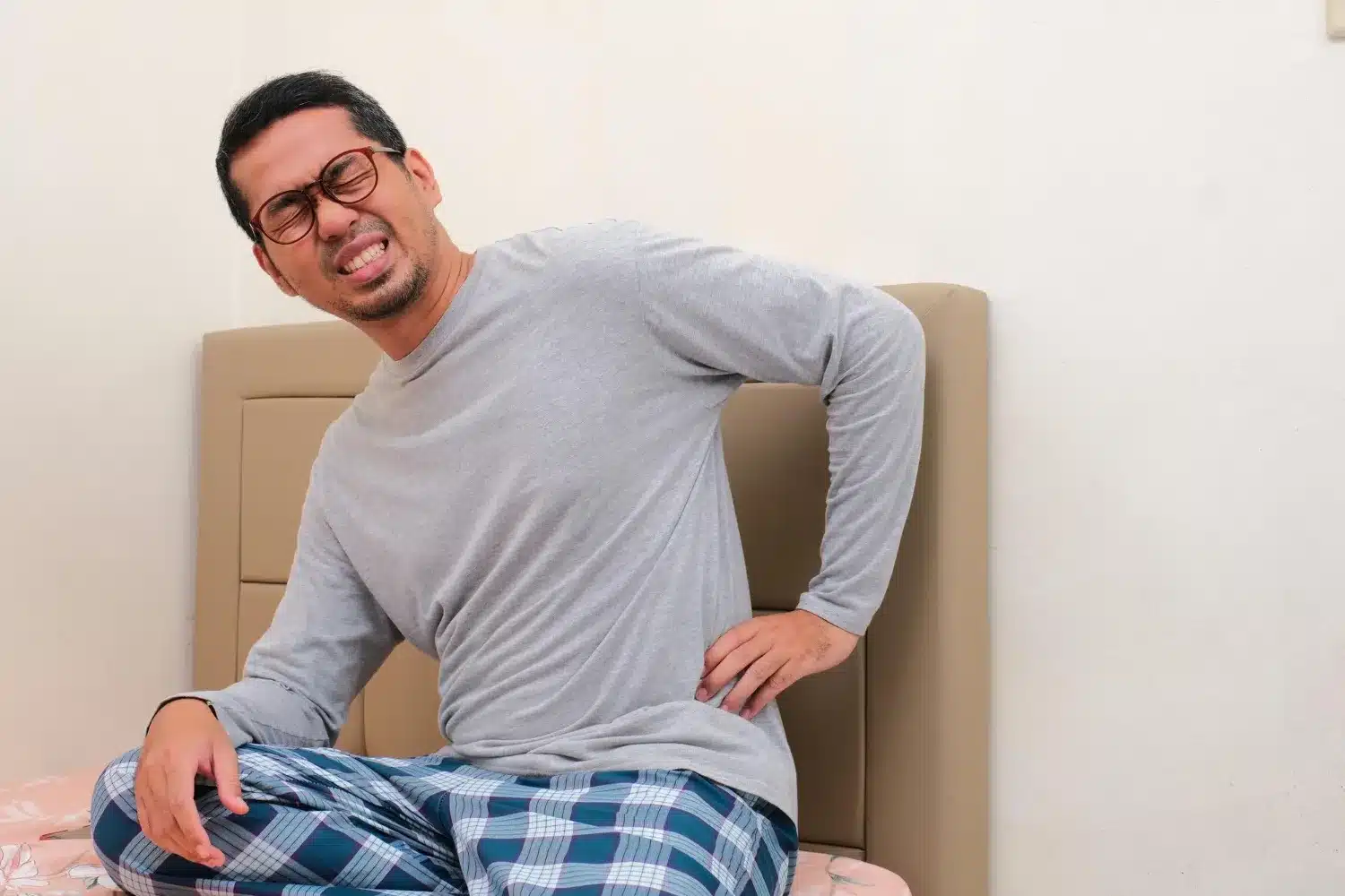 Man experiencing lower back pain while sitting on the floor
