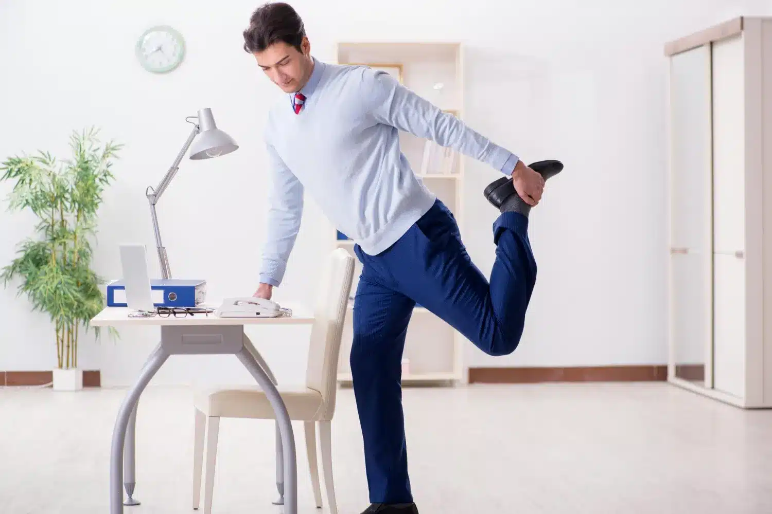 Office worker performing a standing leg stretch during a work break
