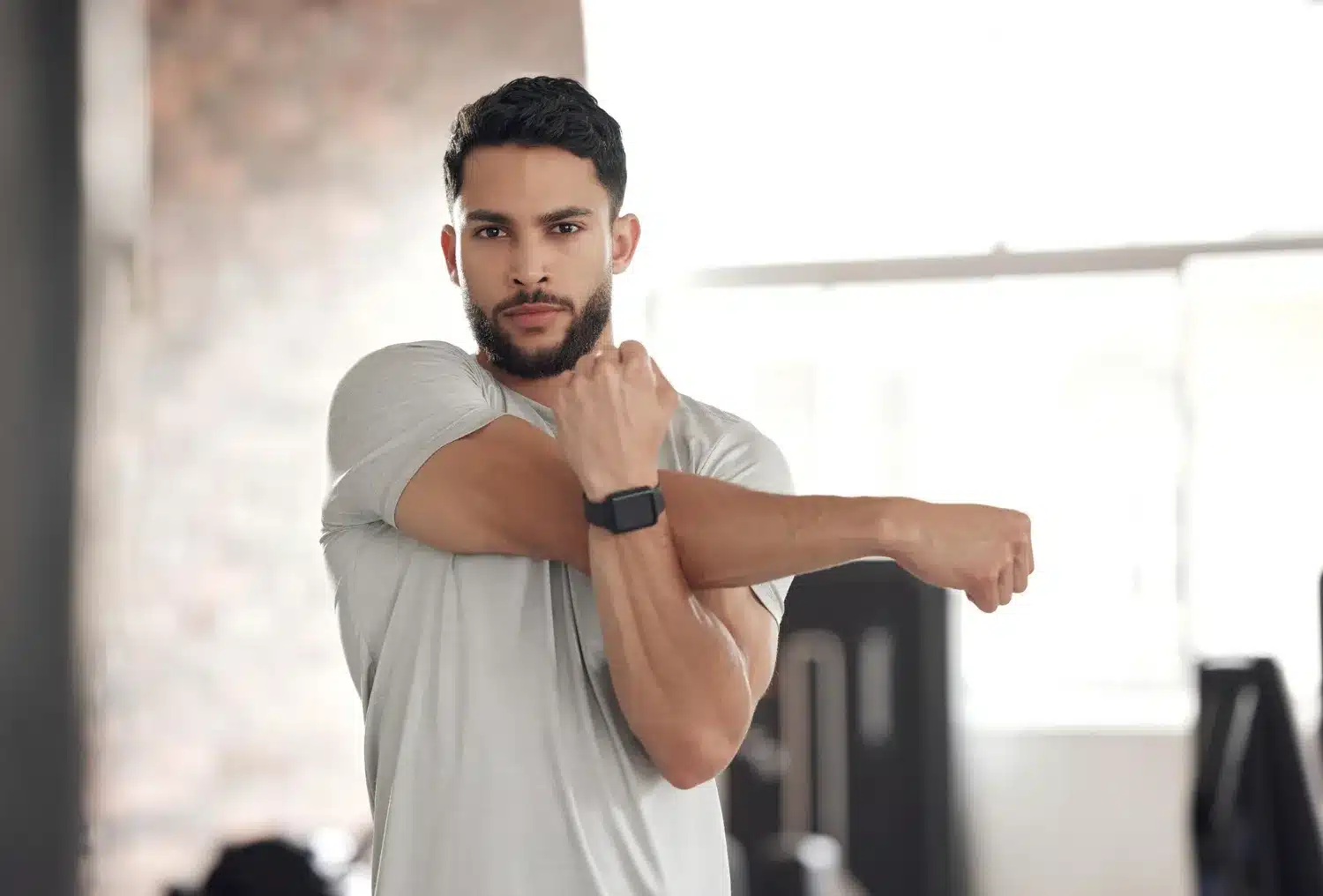 Man performing a cross-body shoulder stretch at home