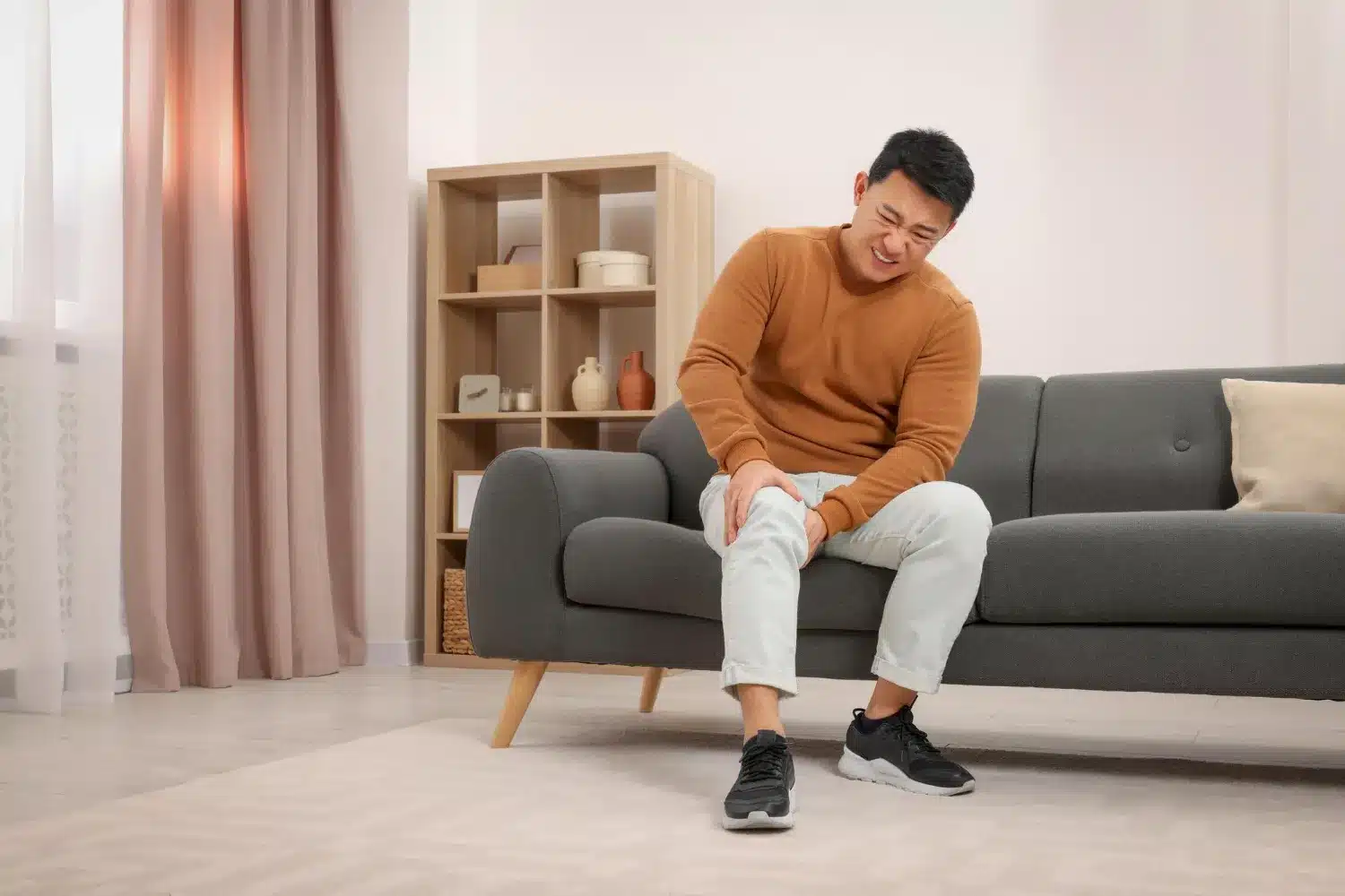 Man holding his knee while sitting on a sofa