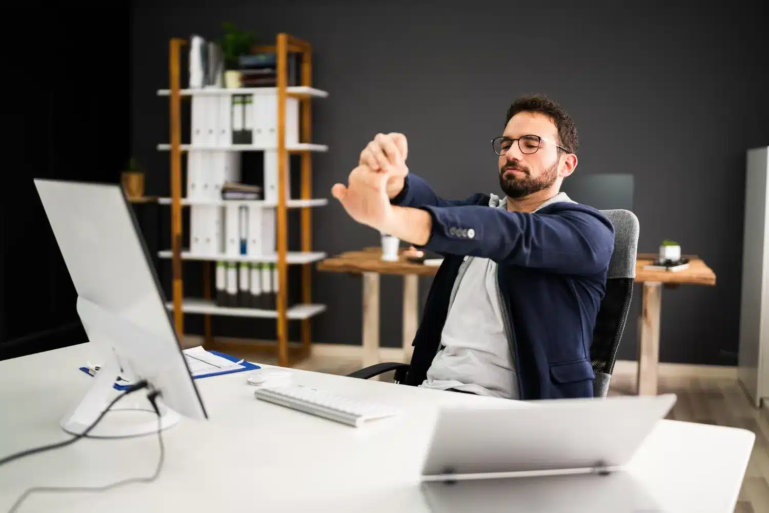 Office worker performing a seated shoulder stretch at a desk