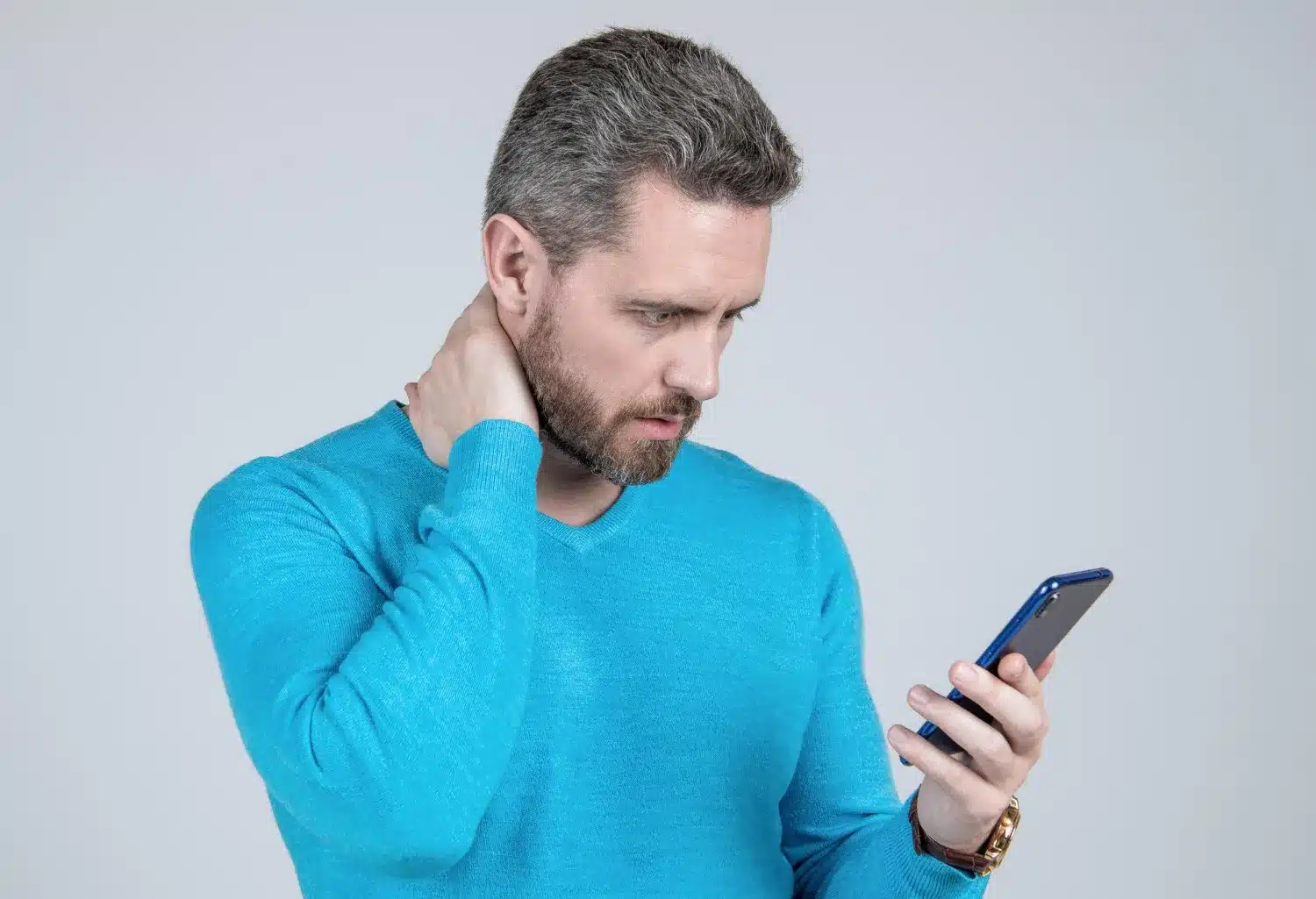 Man experiencing neck and shoulder discomfort while using a smartphone