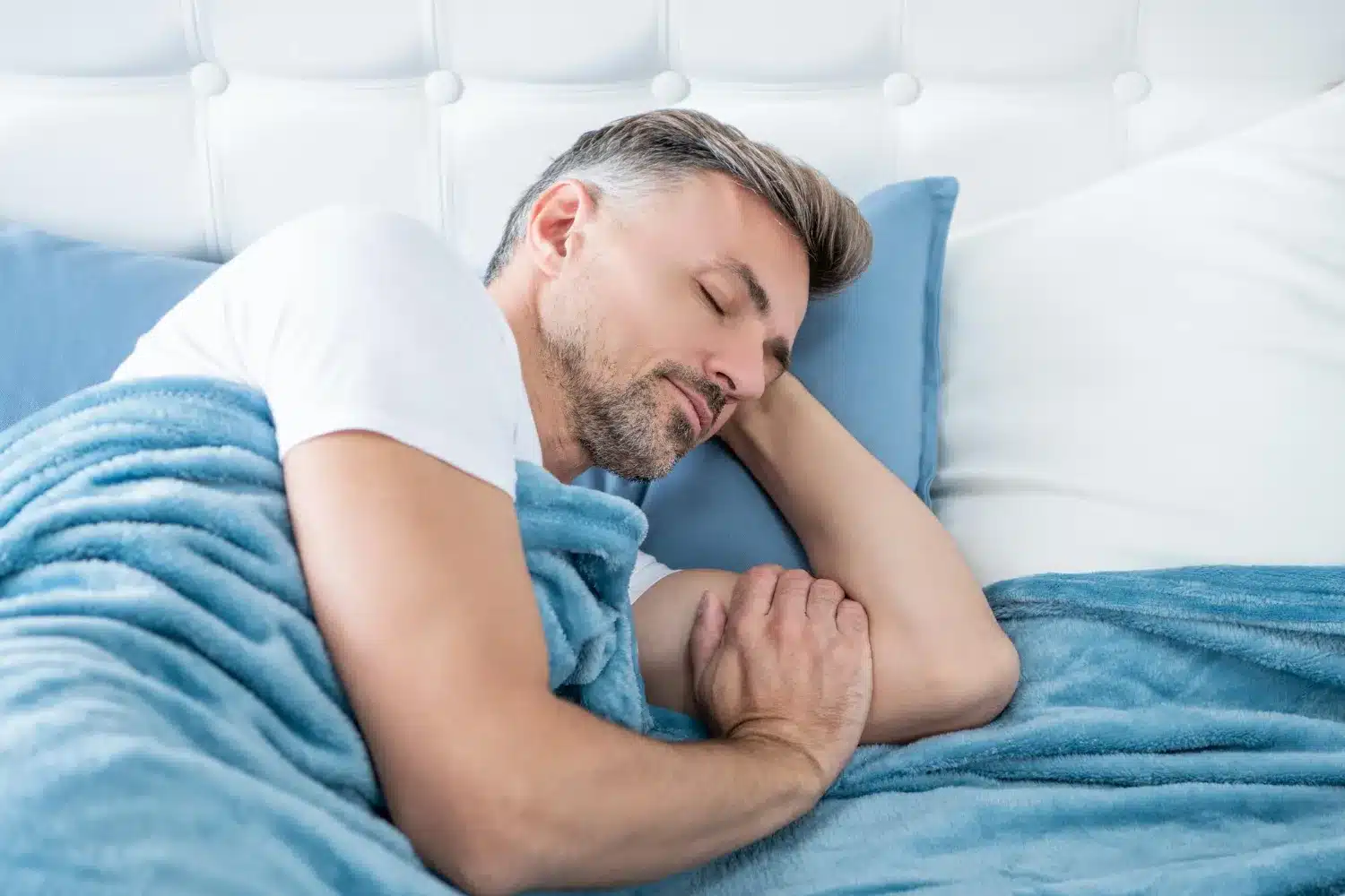 Man sleeping on his back with his head supported by a pillow