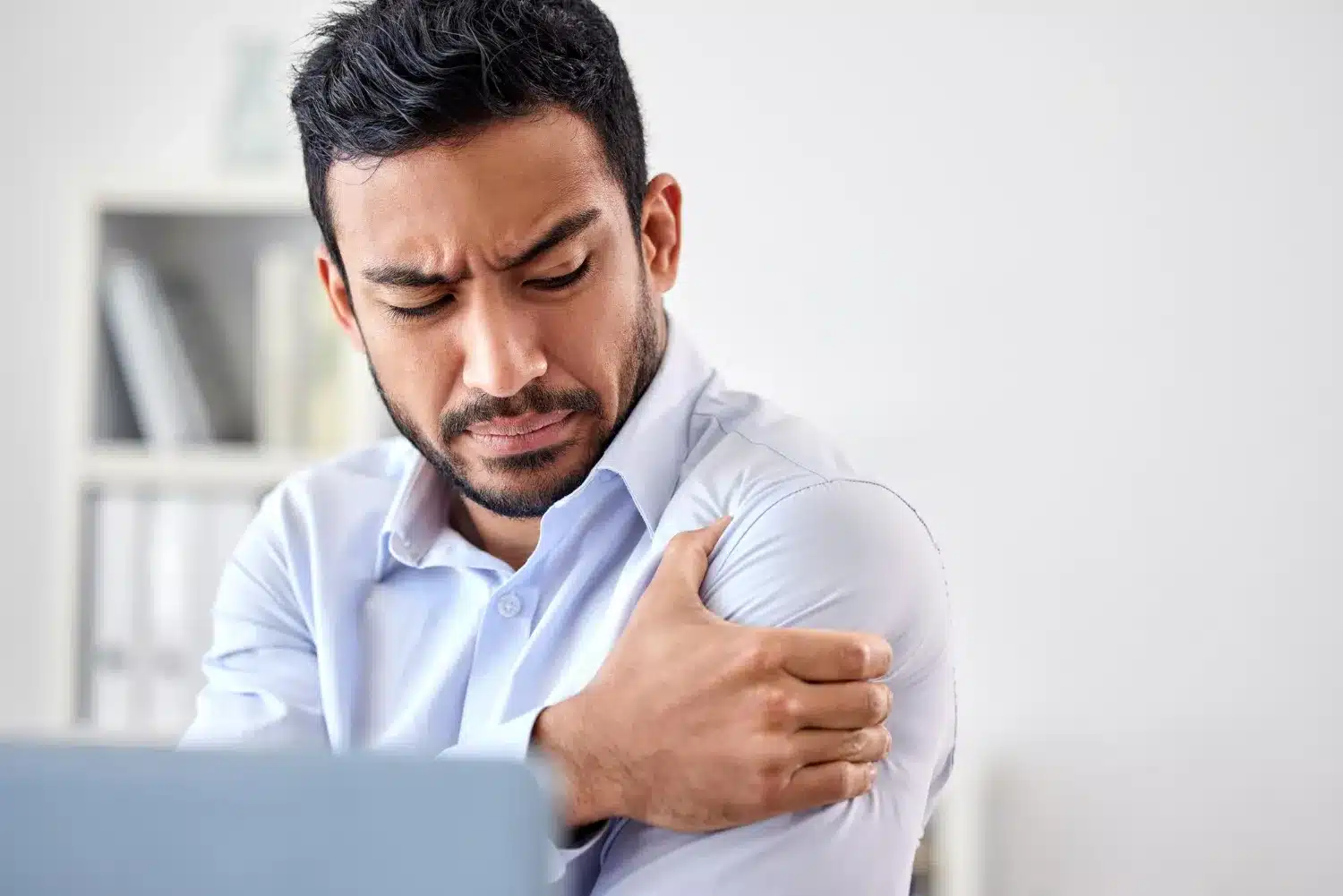 Man holding his shoulder while experiencing shoulder pain